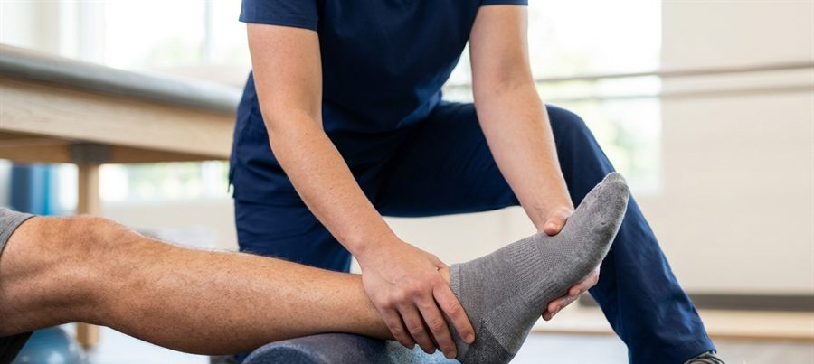 A therapist supporting a patient's leg during a guided stretch